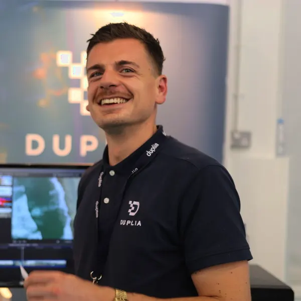 A Duplia team member on the Duplia stand, beside an editing workstation