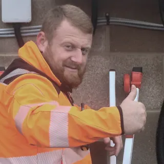 A Duplia engineer in hi-vis giving a thumbs up beside a newly fitted cabinet