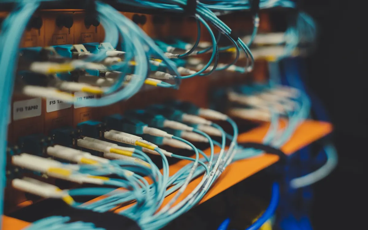 Rows of pale blue fibre patch leads with yellow connector boots plugged into a patch panel