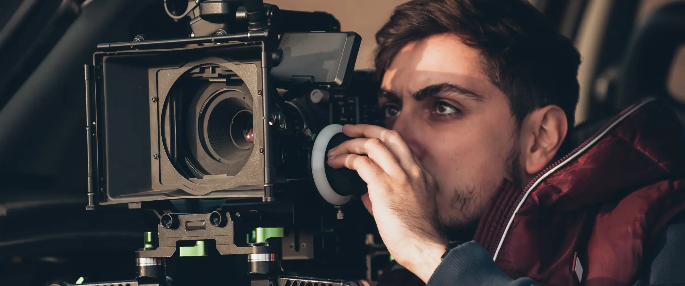 A camera operator pulling focus on a cinema camera during a shoot